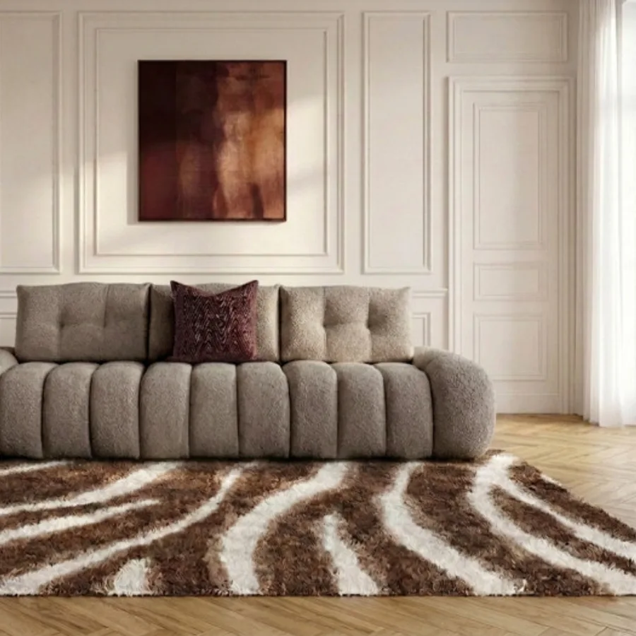 Canapé Apollon taupe clair dans salon, tapis zèbre marron blanc, tableau abstrait.