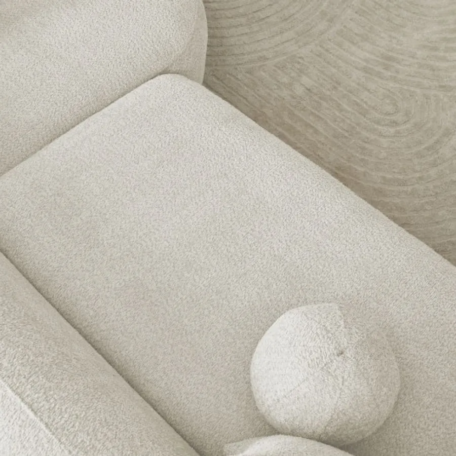 Gros plan sur les coussins ronds et le tissu bouclette du canapé Ashley en blanc.