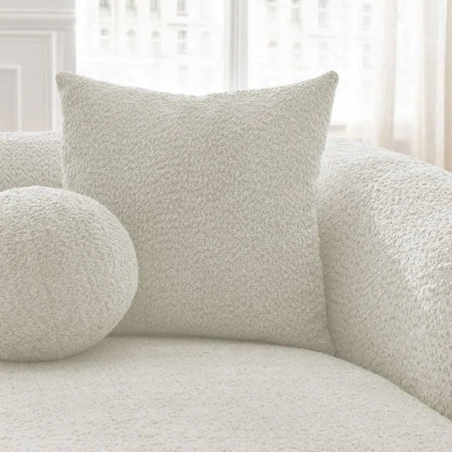 Gros plan des coussins carrés et ronds en bouclette du canapé Ashley en blanc.
