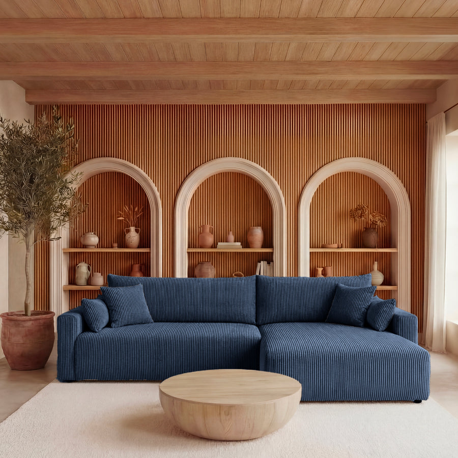 Canapé Boria angle bleu foncé côtelé dans salon clair avec niches et objets décoration.