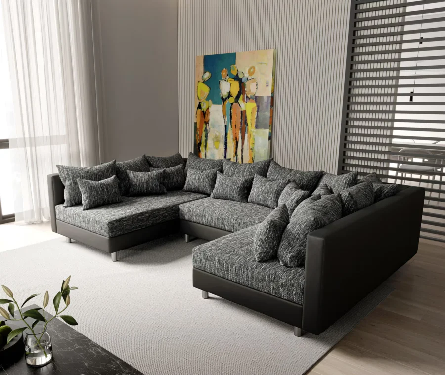 Canapé Clovis en U en tissu anthracite chiné et simili cuir noir, devant un tableau coloré.