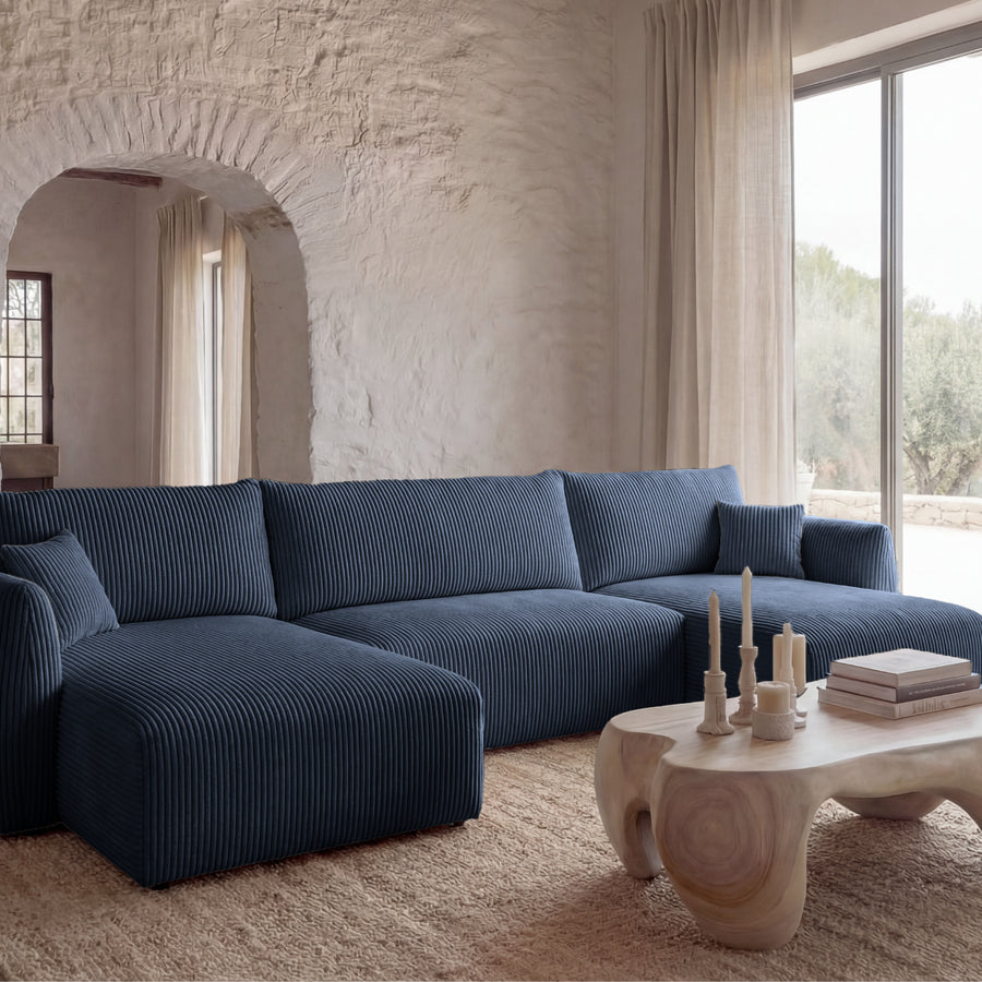 Canapé Elio panoramique en tissu bleu marine, salon blanc avec grandes baies vitrées