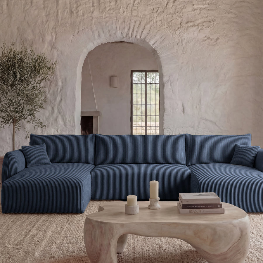 Canapé Elio panoramique bleu marine angle, pièce blanche, table bois naturel, plantes
