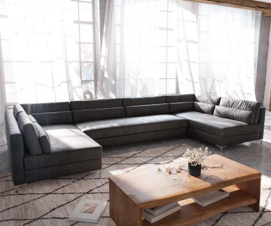 Canapé Elio panoramique en tissu gris anthracite dans une pièce claire aux grandes fenêtres et rideaux blancs.