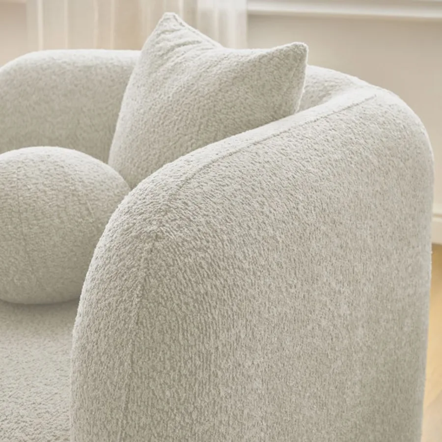 Gros plan sur la texture bouclette et les formes arrondies du canapé Hailey blanc cassé.
