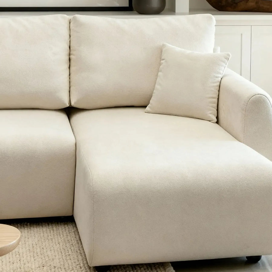 Détail de l'angle du canapé Hera en tissu beige avec ses coutures apparentes.
