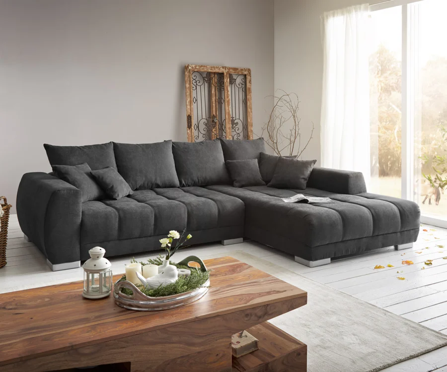 Canapé Josea d’angle en tissu gris anthracite, méridienne à droite, dans un salon au parquet clair.