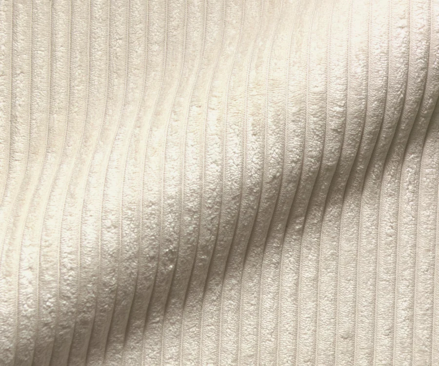 Gros plan du velours côtelé beige aux côtes larges et au toucher peluché.