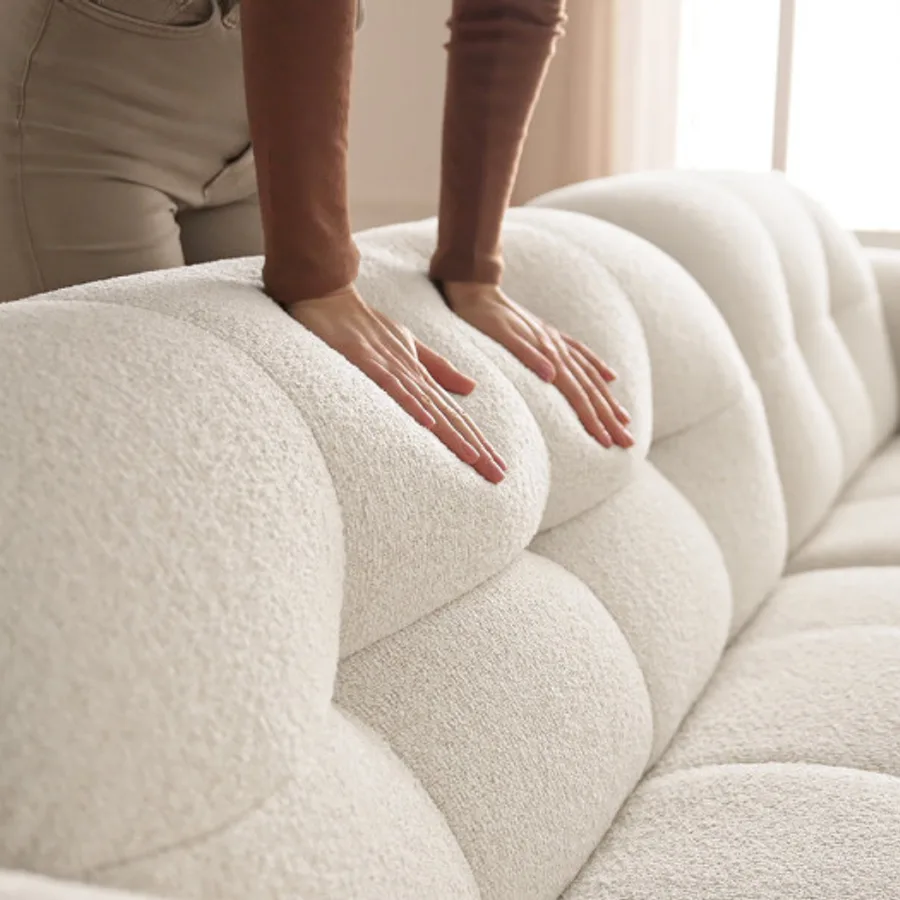 Gros plan sur la texture du tissu beige et les formes molles du canapé Laura.