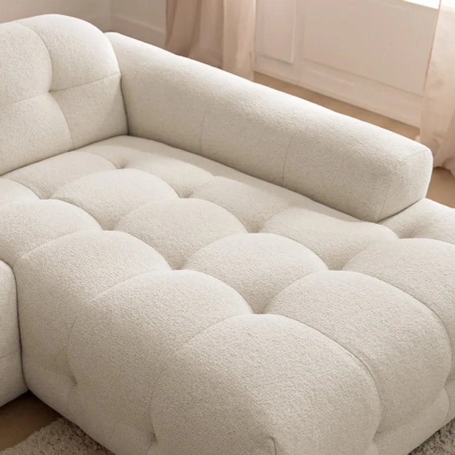 Gros plan sur les coussins capitonnés et la texture du tissu beige du canapé Laura.
