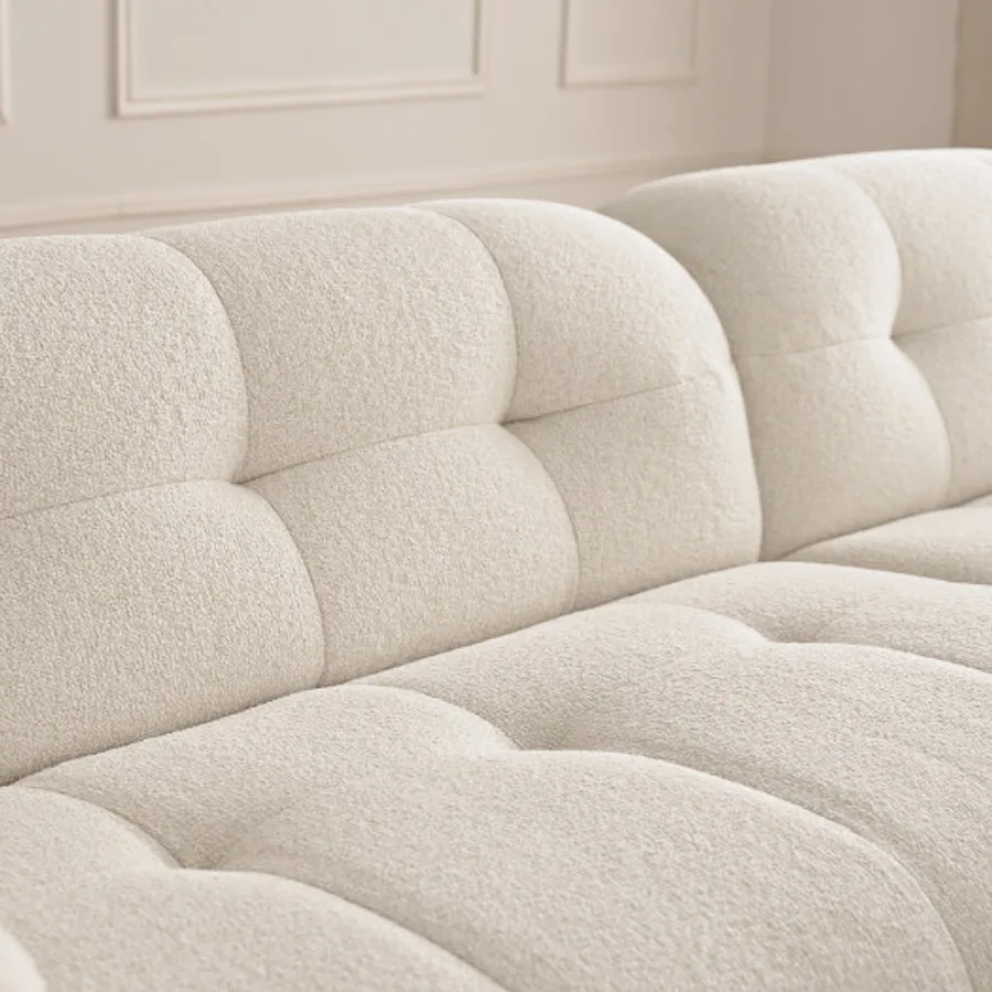 Vue rapprochée des accoudoirs et du capitonnage du canapé Laura en beige.