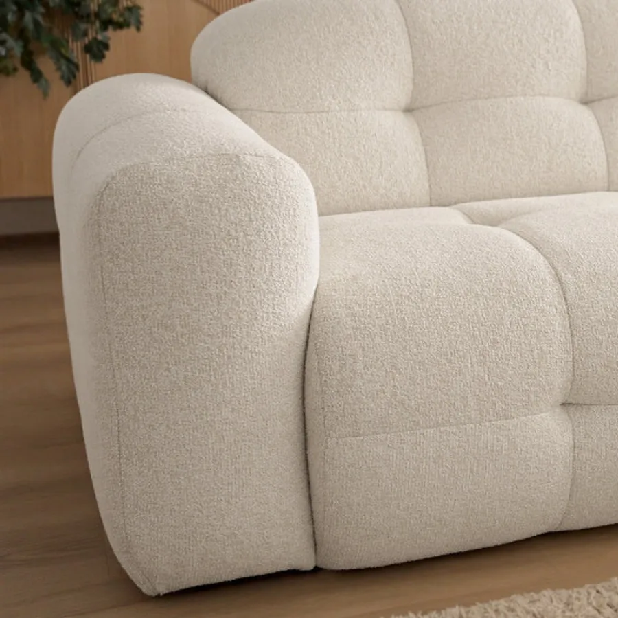 Détail du bras arrondi et des coussins gonflants du canapé Laura beige.