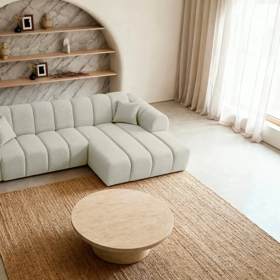 Canapé Laura d'angle en tissu beige clair, dans un salon avec table basse ronde en bois.