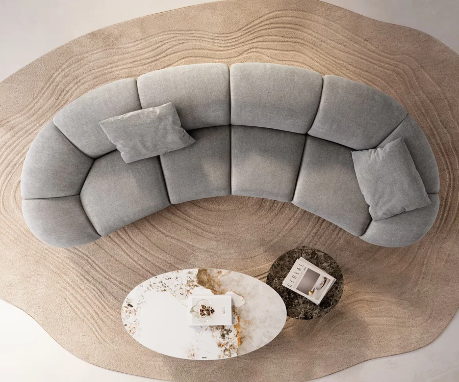 Vue de dessus du canapé courbé gris avec deux coussins et deux tables basses.