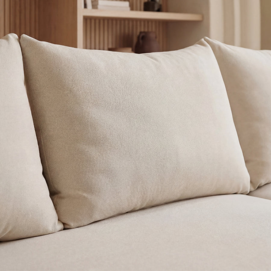 Détail des coussins rectangulaires du canapé Océane en tissu beige clair.