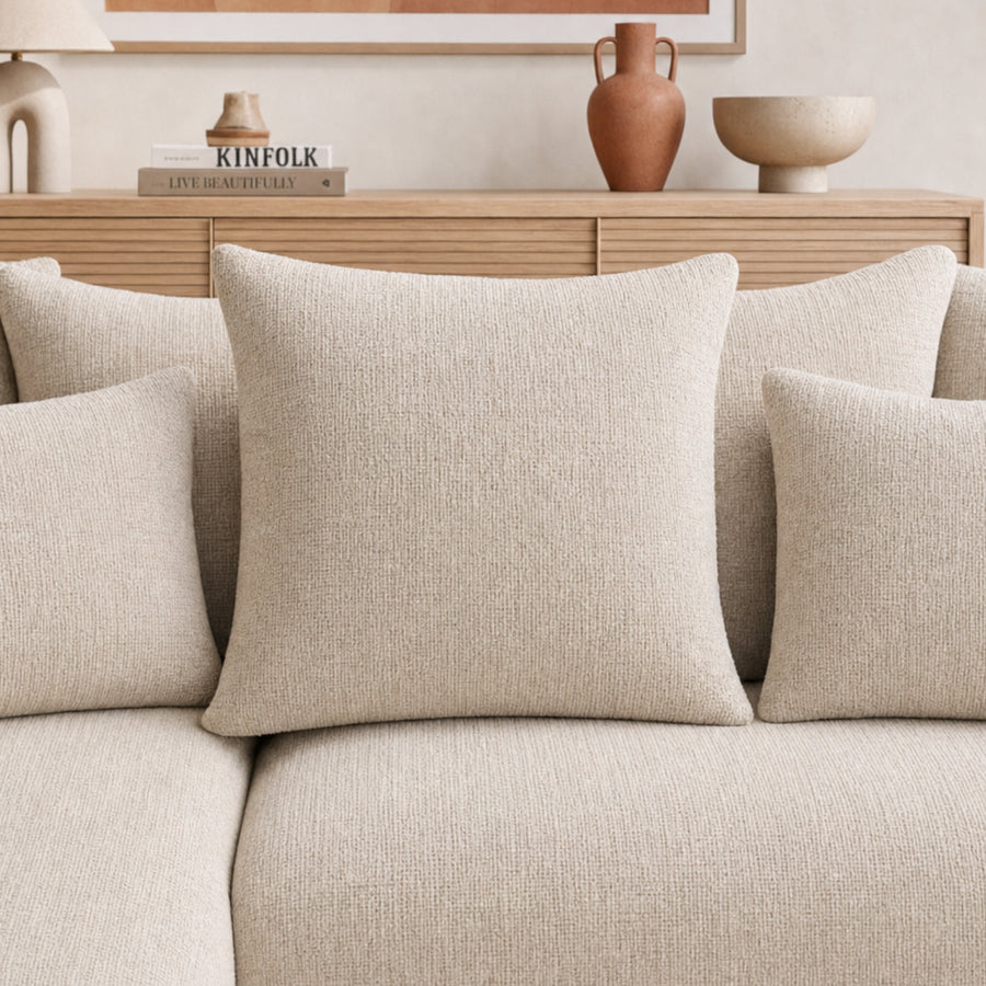 Détail des coussins de décoration du canapé Portofino en tissu beige clair.