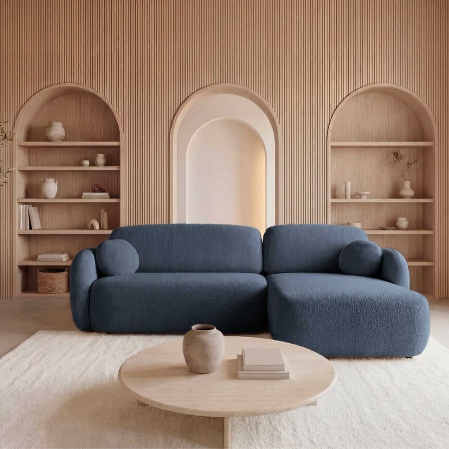 Canapé Santiago angle en tissu bleu foncé, méridienne droite, dans salon beige avec étagères