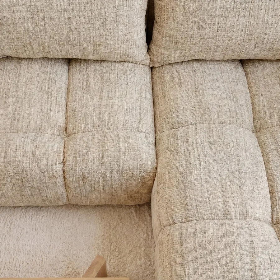Gros plan sur les coussins matelassés de l'assise du canapé Sintra en tissu beige clair.
