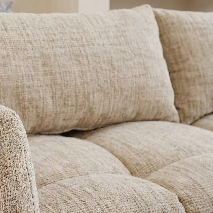 Gros plan sur les coussins de dossier et les accoudoirs arrondis du Sintra en tissu beige.