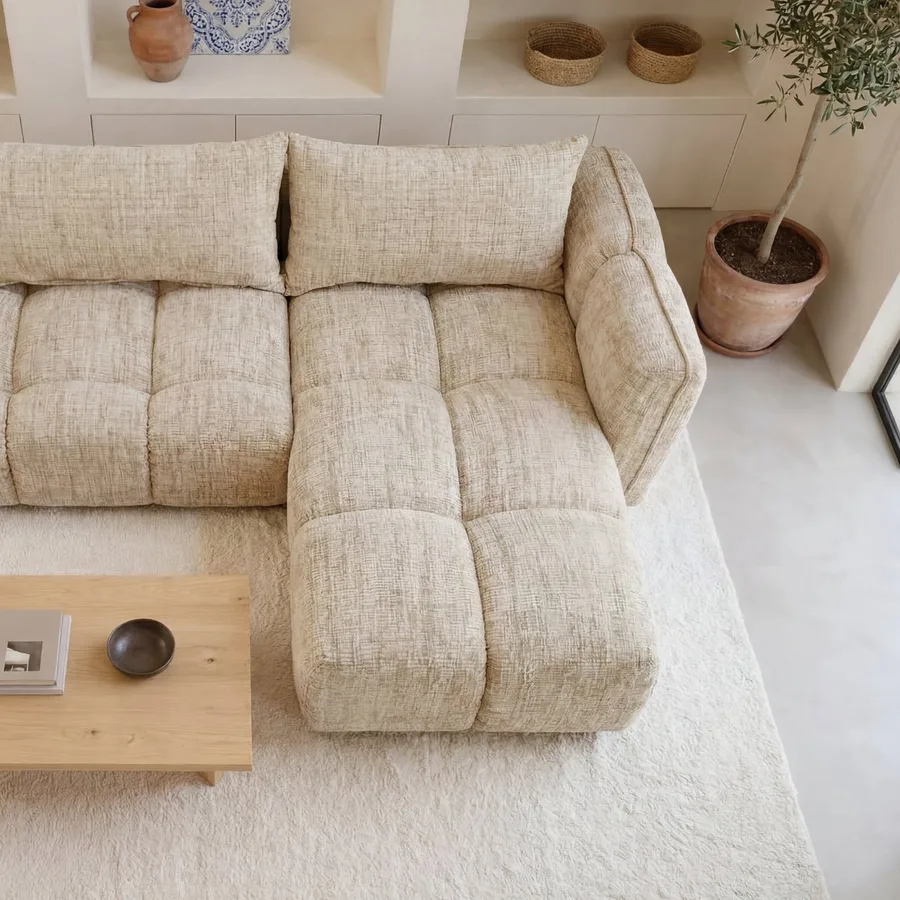 Vue de dessus du canapé d'angle Sintra beige avec méridienne, table basse en bois, étagères blanches.