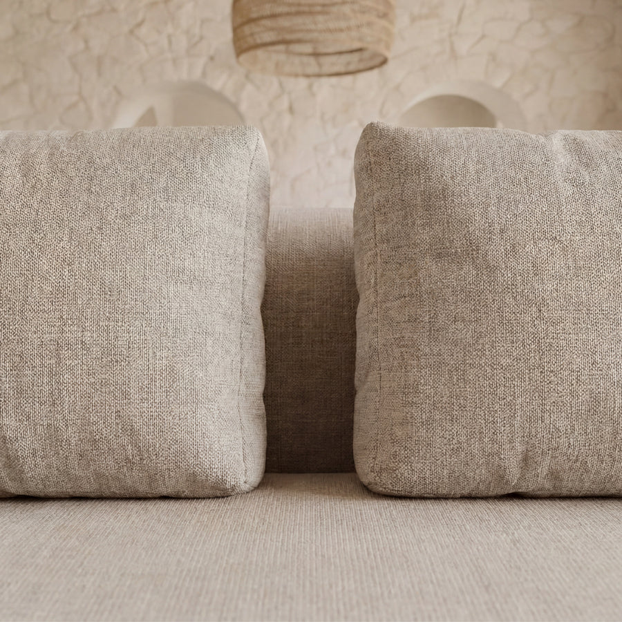 Gros plan des coussins de dossier du canapé Tina en tissu gris clair.