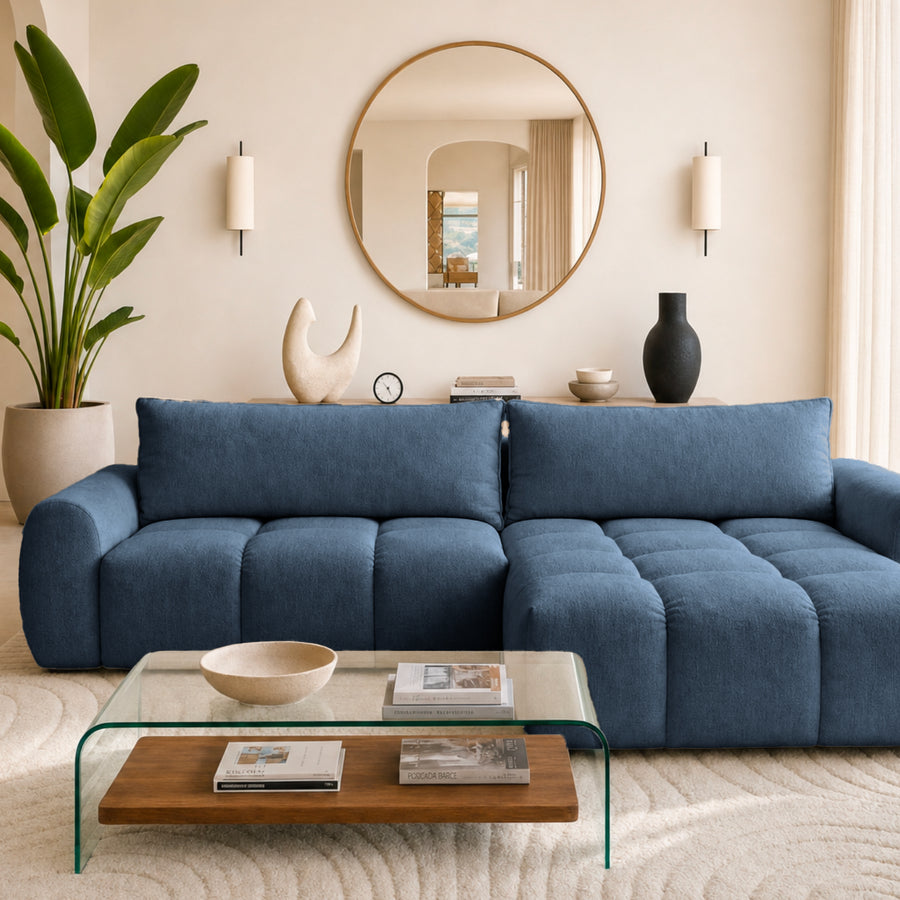 Canapé Viana d'angle en tissu bleu marine, méridienne à droite, dans un salon lumineux avec baie vitrée.
